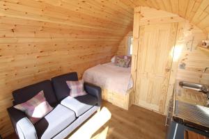 um quarto com uma cama e um sofá numa cabana de madeira em Keepers Pod em Arisaig