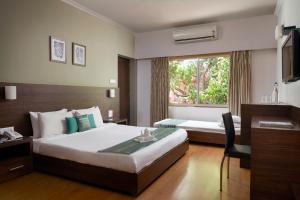 a hotel room with a bed and a desk and a window at The Hawaii Comforts Panjim in Panaji