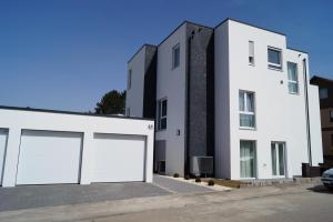 un edificio blanco con dos puertas de garaje delante de él en Ferienwohnung Alona, en Engelsbrand