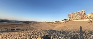 una playa de arena con edificios en el fondo en Pluk de dag, en Oostduinkerke