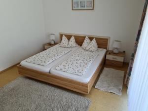 um quarto com uma cama com lençóis brancos e almofadas em Alpenpension Bergidyll em Schönau am Königssee