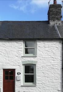 a white brick building with a window and a door at Tri deg un, cottage for 2 adults and 2 children in Machynlleth