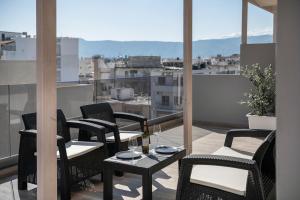 a balcony with chairs and a table with wine glasses at Morum City Hotel Chania in Chania