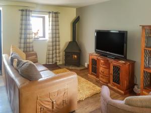 a living room with a couch and a flat screen tv at Rambler's Cottage in Tansley