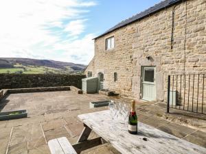 a bottle of wine on a wooden table in front of a stone building at Broadwood Barn in Hathersage