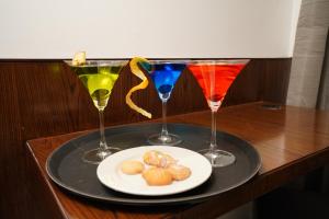 a tray with three wine glasses and a plate of food at Kyriad Vajram Guntur in Guntūr