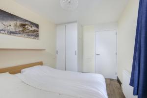 a bedroom with a white bed and a blue curtain at DE TRINTEL met zeezicht in Egmond aan Zee