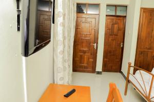 une chambre avec deux portes, une table et une télévision dans l'établissement Maresi Luxury Hotel, à Arusha