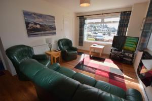 a living room with a green leather couch and a television at Armadale Cottage in Lochgoilhead