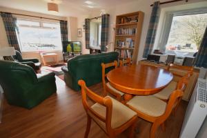 a living room with a wooden table and green chairs at Armadale Cottage in Lochgoilhead