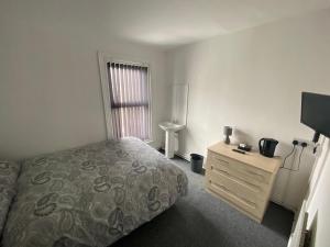 a bedroom with a bed and a dresser and a window at The Honley hotel in Blackpool