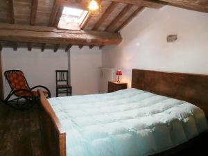 a bedroom with a large bed and a chair at Antico Fienile in Serravalle