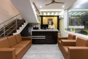 a man standing at a desk in a lobby with chairs at Hotel Mookambika Comforts in Tirupati