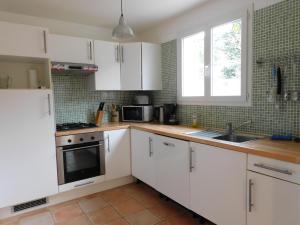 a kitchen with white cabinets and a sink and a window at Bergerie Du Plo in Montlaur