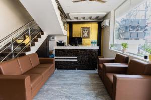 a waiting room with brown leather couches and a bar at Hotel Mookambika Comforts in Tirupati