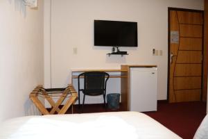 a bedroom with a desk with a television and a bed at Los Lagos Resort Hotel in Capiatá