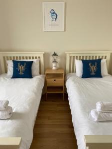 two beds with blue and white pillows in a room at Breakwater in North Berwick
