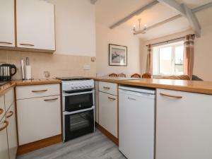 a kitchen with white cabinets and a stove top oven at The Cottage in Holsworthy