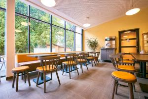 Jugendherberge Detmold في ديتمولد: مطعم بطاولات وكراسي ونوافذ كبيرة