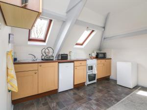 an attic kitchen with wooden cabinets and white appliances at The Loft in Holsworthy