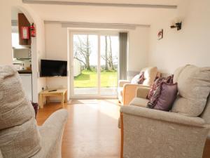 a living room with two chairs and a television at The Stables in Holsworthy