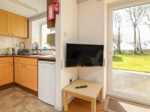 a kitchen with a tv on the wall and a table at The Stables in Holsworthy