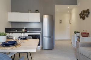 a kitchen with a stainless steel refrigerator and a table at Carignano Design Apartments by Wonderful Italy in Genoa