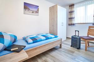 una habitación con una cama y una silla con una maleta en Ferienhof Halbig, en Riedenburg