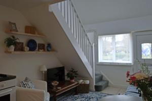 a living room with a staircase with a couch and a table at Charming 1-Bed cottage in Pembroke close to castle in Pembroke