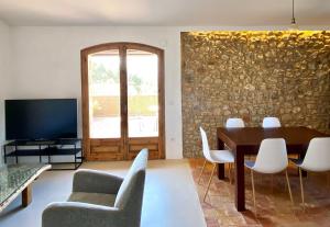 sala de estar con mesa, sillas y TV en Els Olivars, en Bellcaire dʼEmpordà