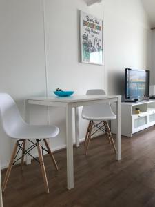 uma mesa branca com duas cadeiras e uma televisão em Brighton Marina Floating home em Brighton & Hove
