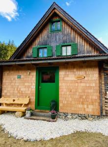 una casa con una puerta verde y un banco en Zirbitz Hütte mit Sauna und Kamin, en Sankt Lambrecht