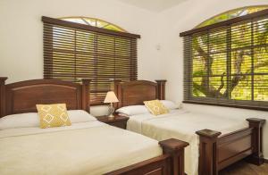 two beds in a room with two windows at The Amazing Hispaniola Villa 145 in Sosúa