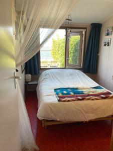 a bed in a bedroom with a window and a bedspread at The Outpost Lakehouse- enjoy our house at Reeuwijkse Plassen - near Gouda in Reeuwijk