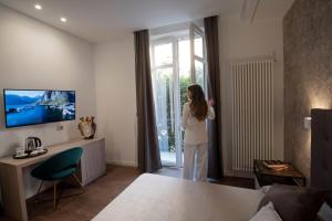 een vrouw in een woonkamer die uit het raam kijkt bij Fervore Luxury Rooms in Palermo