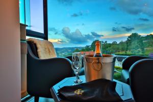 a bottle of champagne in a bucket on a table with a glass at Caminho das Pedras Pousada de Charme in Campos do Jordão