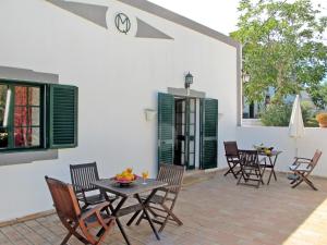 een patio met houten stoelen en een tafel met fruit erop bij Holiday Home Quinta da Murteira - FUZ101 by Interhome in Fuzeta