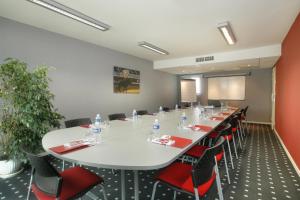 a conference room with a large white table and red chairs at The Originals City, Hôtel Les Thermes de l'Avenue, Dax in Dax