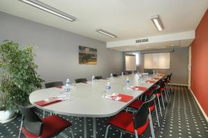 una sala de conferencias con una gran mesa blanca y sillas rojas en The Originals City, Hôtel Les Thermes de l'Avenue, Dax, en Dax