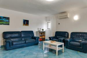 a living room with two blue leather couches and a table at InVilla Seristori, a 50 m dal mare in San Vincenzo