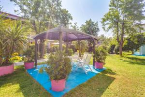 a gazebo with a table and chairs and plants at Blu Marlin Residence con piscina in Lido Adriano