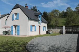 Biały dom z niebieskimi oknami i ogrodzeniem w obiekcie Gite Ladagnous w mieście Peyrouse