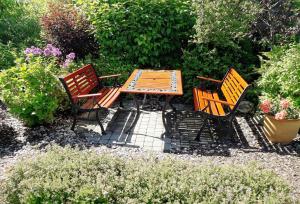 a wooden table and three chairs in a garden at morska chata in Lubiatowo