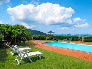 una piscina con due sedie bianche in erba di Apartment Stalla by Interhome a Sasso Pisano