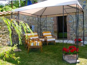 Apartment Stalla by Interhome في Sasso Pisano: طاولة وكراسي تحت مظلة بيضاء