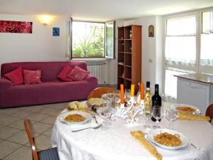Apartment Mandarino by Interhome في مونتينيوزو: طاولة مع أطباق من الطعام وأريكة أرجوانية