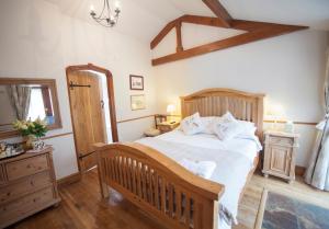 1 dormitorio con cama grande y banco de madera en Beeches Farmhouse Country Cottages & Rooms, en Bradford on Avon