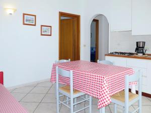 uma cozinha com uma mesa e cadeiras vermelhas e brancas em Apartment Abete by Interhome em Capoliveri