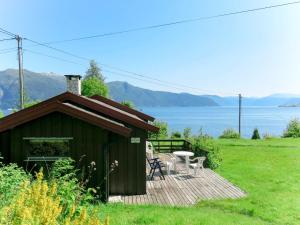 eine Hütte mit einer Terrasse mit einem Tisch und Stühlen in der Unterkunft Chalet Skåsheim - FJS023 by Interhome in Balestrand