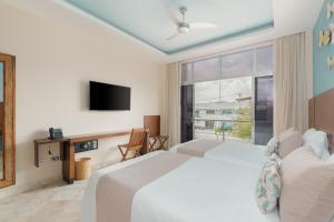 a hotel room with a bed, tv, and couch at Biwa Tulum in Tulum